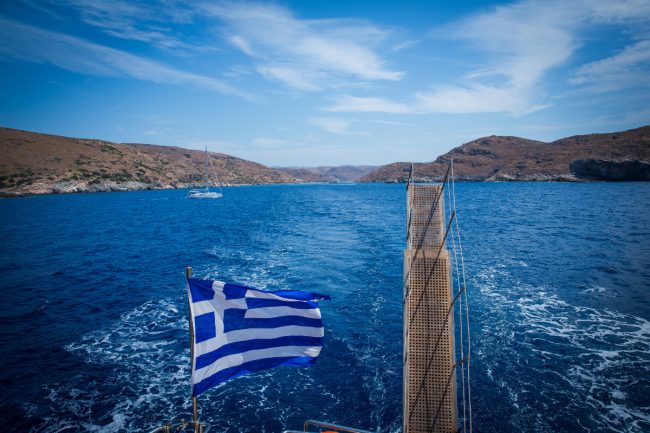 Island hopping in the Cyclades Greece flag seen from a moving ship